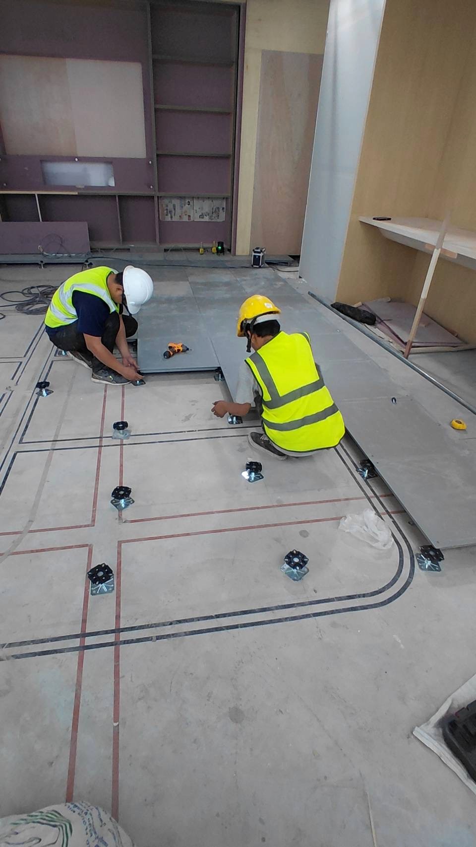 Rhino installers laying raised floor panels on pedestals